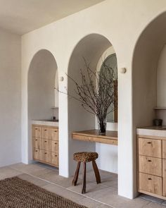 a bathroom with an arched wall and wooden stools in it, along with two sinks