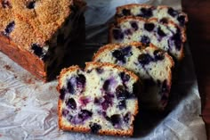 sliced blueberry bread sitting on top of a piece of wax paper next to it