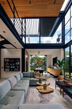 a living room filled with lots of furniture under a wooden ceiling above a large window