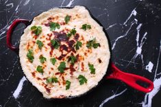 a pan filled with food sitting on top of a black counter next to a red spatula