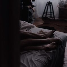 two people are laying on a bed in the dark with their bare legs spread out