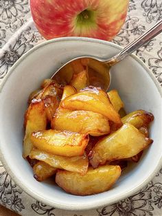 a bowl filled with apple slices next to an apple on top of a floral table cloth