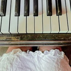 a person's feet resting on the edge of a piano