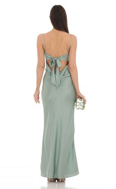 a woman in a long green dress with a back cutout and bow at the waist