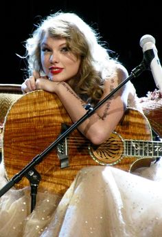 a woman with tattoos on her arm holding a guitar