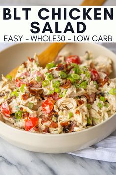 a white bowl filled with chicken salad next to a wooden spoon