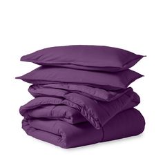 four pillows stacked on top of each other with purple sheets and pillow cases in the background