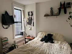 an unmade bed in a small room with books on the wall and pictures above it