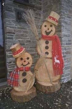 two wooden snowmen standing next to each other in front of a brick wall and door