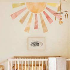 a white crib with a painting on the wall and an art piece hanging above it