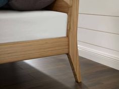 a wooden bed frame sitting on top of a hard wood floor next to a white wall