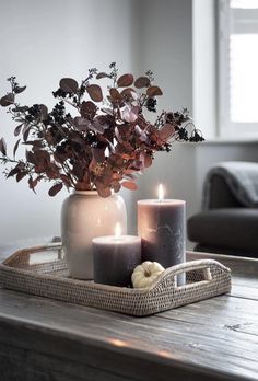 two candles are sitting on a tray next to a vase with some flowers in it