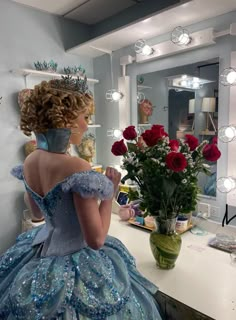 a woman in a blue dress is looking at herself in the mirror with roses on her head