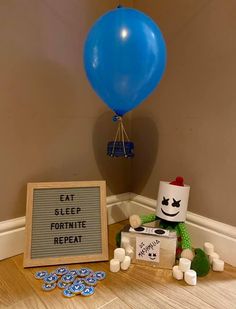 a blue balloon and some white candles on a wooden floor with a sign that says eat sleep fortte repeat