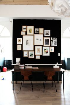 a table with chairs and pictures on the wall behind it in a room that has wood flooring