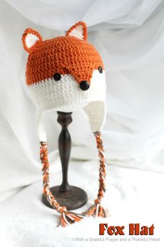 an orange and white knitted fox hat on top of a mannequin head