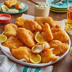 a plate full of fried chicken with lemon wedges and dipping sauce on the side