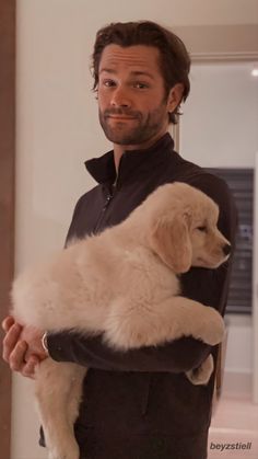 a man holding a white puppy in his arms