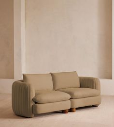 a beige couch sitting on top of a hard wood floor next to a white wall