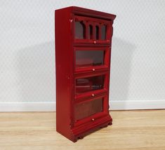 a tall red cabinet sitting on top of a wooden floor