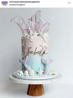 there is a pink and blue cake with mermaid decorations on the top that says fabelke