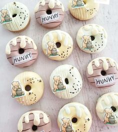 twelve donuts with cartoon characters on them sitting on a white table top, all decorated in pastel colors