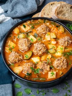 meatball soup in a black bowl with bread on the side