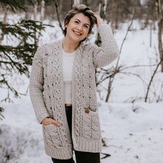 a woman standing in the snow wearing a cardigan