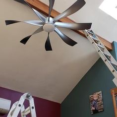 a ceiling fan that is mounted to the side of a wall in a room with purple walls