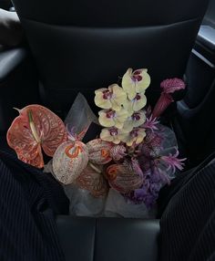 flowers are placed in the center console of a car, with other items sitting on the floor