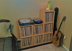 a record player sitting on top of a wooden shelf next to a bookcase filled with records