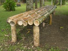 a wooden bench made out of logs sitting in the grass