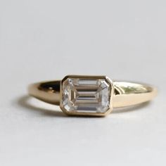 an engagement ring with a baguette cut diamond in the center, on a white background