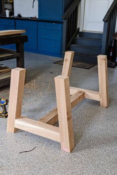 a wooden bench sitting on top of a floor next to a blue cabinet and stairs