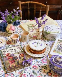 a table topped with books and plates covered in purple flowers