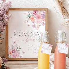 two bottles of juice sitting next to each other on a table with flowers and a sign