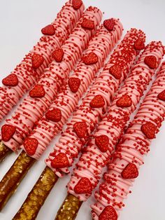 strawberries are arranged on sticks with pink frosting and red sprinkles