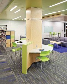 a library with tables, chairs and couches next to bookshelves in it