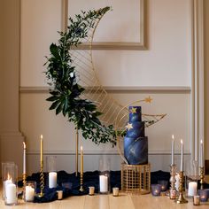 a table topped with candles and a blue cake next to a star decoration on top of it