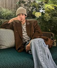 a young man sitting on top of a green couch next to a potted plant