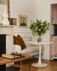 a living room filled with furniture and a fire place next to a white table topped with flowers