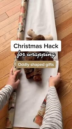 someone wrapping christmas presents on a sheet of paper with the words, christmas hack for wrapping oddly shaped gifts