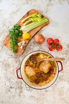 a large pot filled with food on top of a counter next to tomatoes and celery