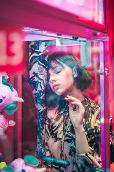 a woman standing in front of a mirror holding a cell phone to her ear and looking at it