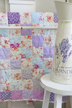 a white stool with a purple and pink quilt on it