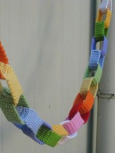 a multicolored crocheted necklace hanging from a hook on a door handle