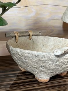 a stone bowl sitting on top of a wooden table next to a potted plant