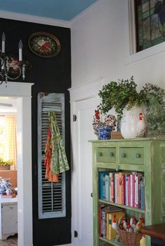 a room with a green cabinet and bookshelf filled with lots of books on top of it