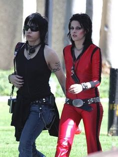 two women dressed in red and black walking on the grass with one holding her hand