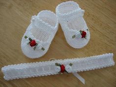 two pairs of white crochet baby shoes with red roses on them